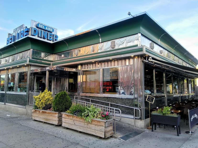 Exterior view of the Bel Aire Diner in Astoria, New York City, featuring its chrome facade, green roof, and blue sign.