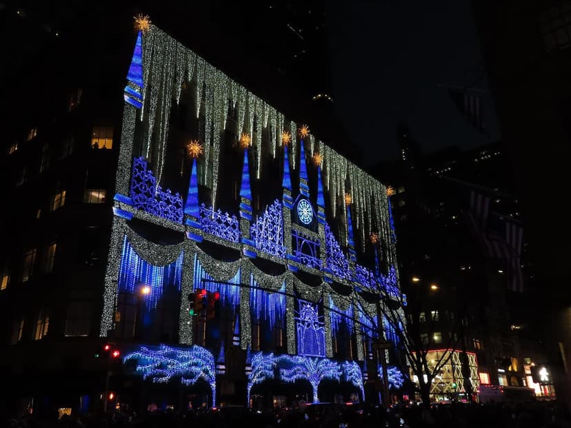 Saks Fifth Avenue department store facade at night, illuminated with an elaborate blue and white holiday light show.