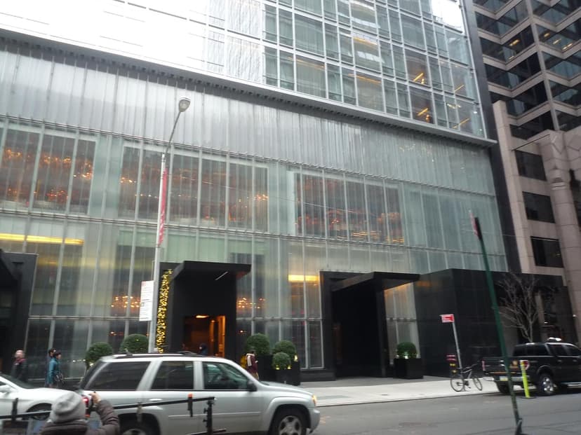 Exterior view of the Baccarat Hotel and Residences on West 53rd Street, showing its modern glass facade and entrances.