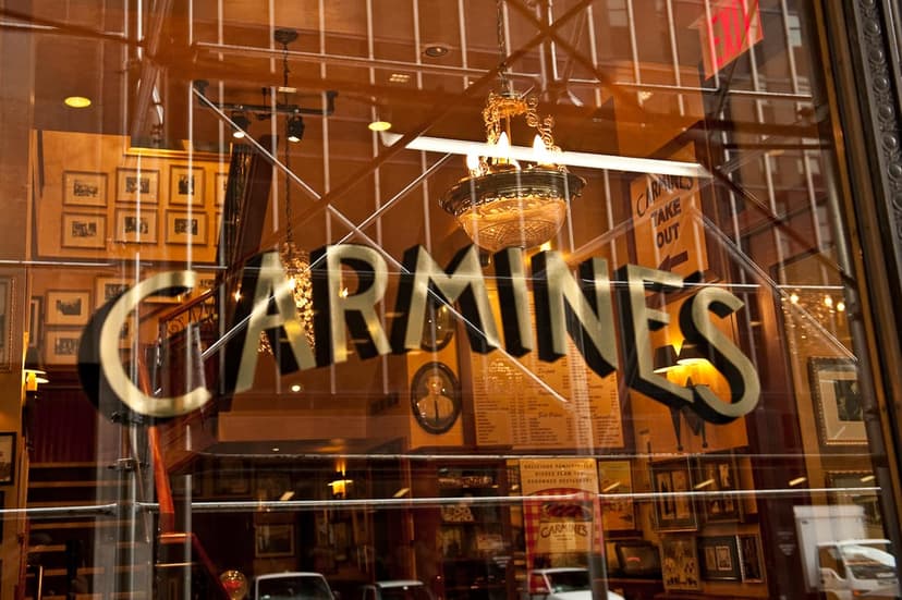 Carmine's restaurant sign on a window, with reflections of the street and the restaurant's interior visible.