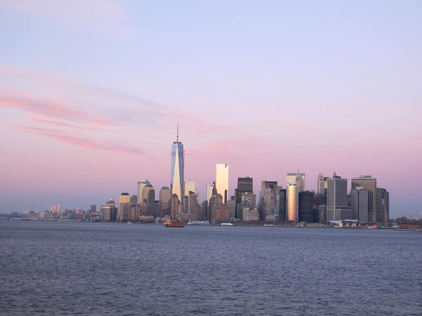 Lower Manhattan skyline with One World Trade Center and other skyscrapers at sunset, viewed from the water with a Staten Island Ferry