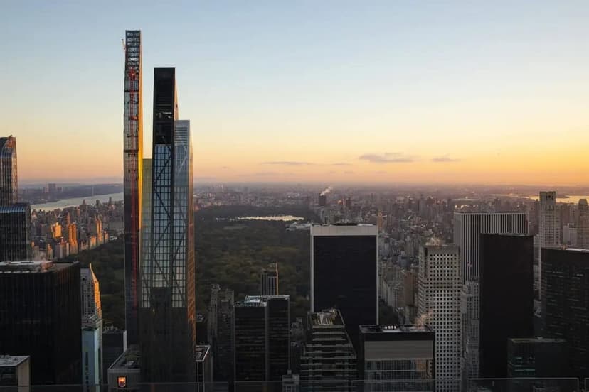 Aerial view of Midtown Manhattan at sunset, showing Central Park, numerous skyscrapers, and the Empire State Building in the distance.
