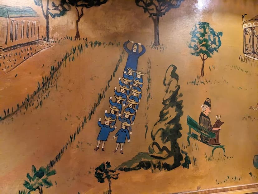 A colorful mural depicting a woman, a line of children, and a person on a bench with a dog in a park setting.