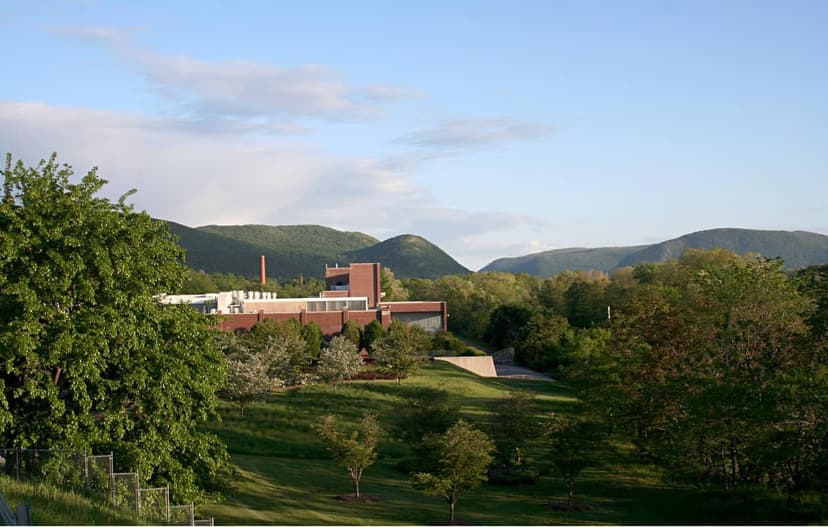 Exterior view of Dia Beacon museum, a modern brick building with large windows, surrounded by green lawns and trees, with mountains in the