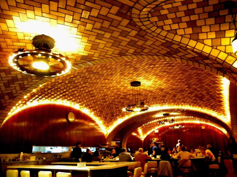 Interior view of the Grand Central Oyster Bar in Grand Central Terminal, featuring its distinctive vaulted, tiled ceilings, warm lighting, and