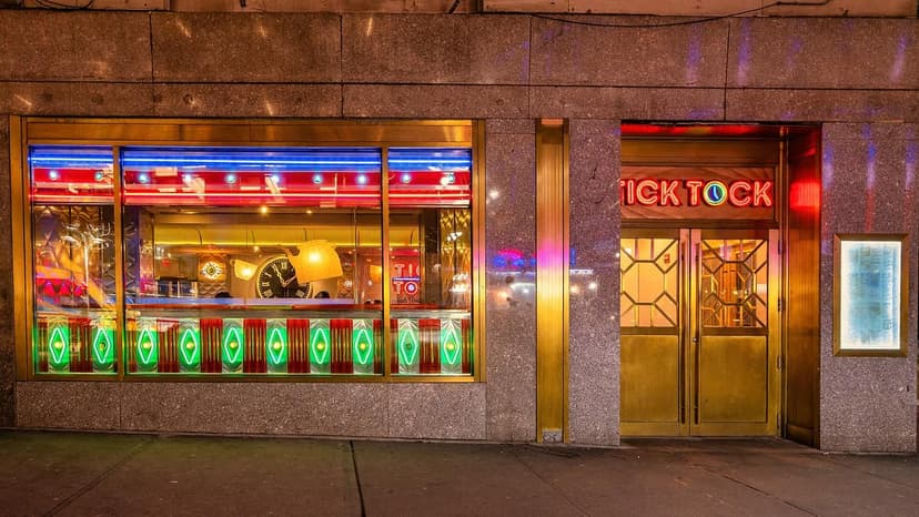 Tick Tock Diner exterior at night with neon signs, illuminated windows, and a gold entrance.