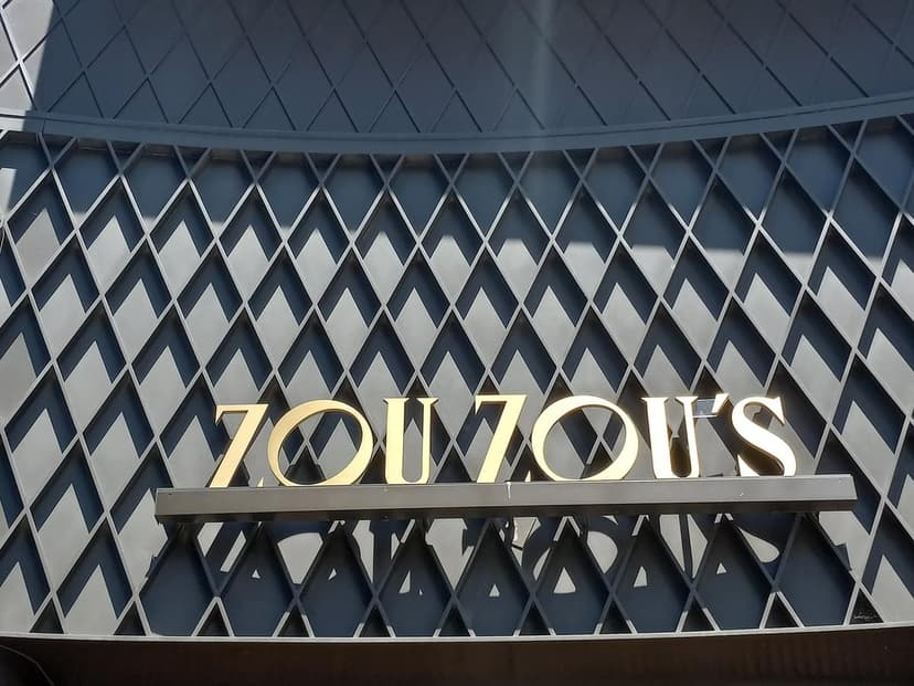 Gold letters spelling ZOU ZOU'S on a dark gray textured wall with a diamond pattern under a curved top.