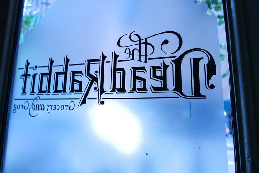 Close up of the mirrored text 'The Dead Rabbit Grocery and Grog' on a frosted glass door